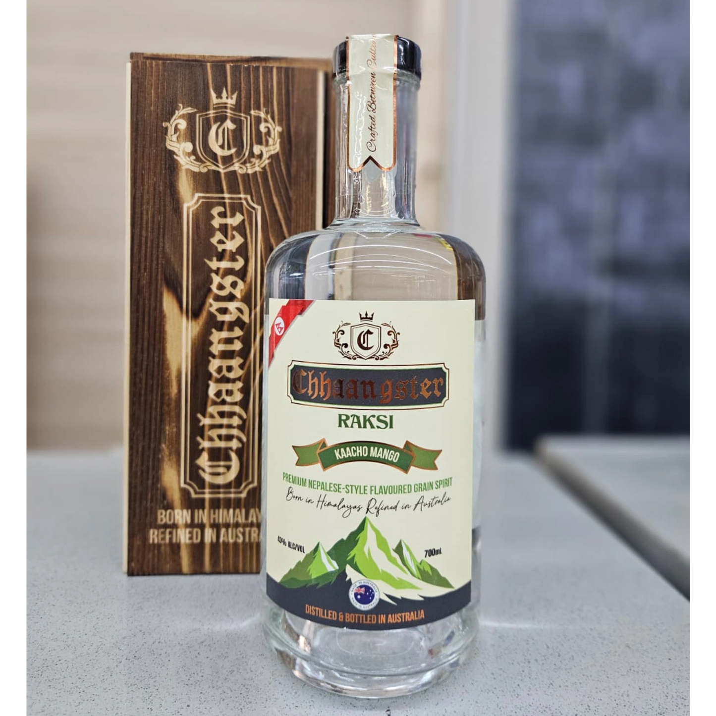 Bottle of Chhaanster Raksi with wooden box on a neutral background